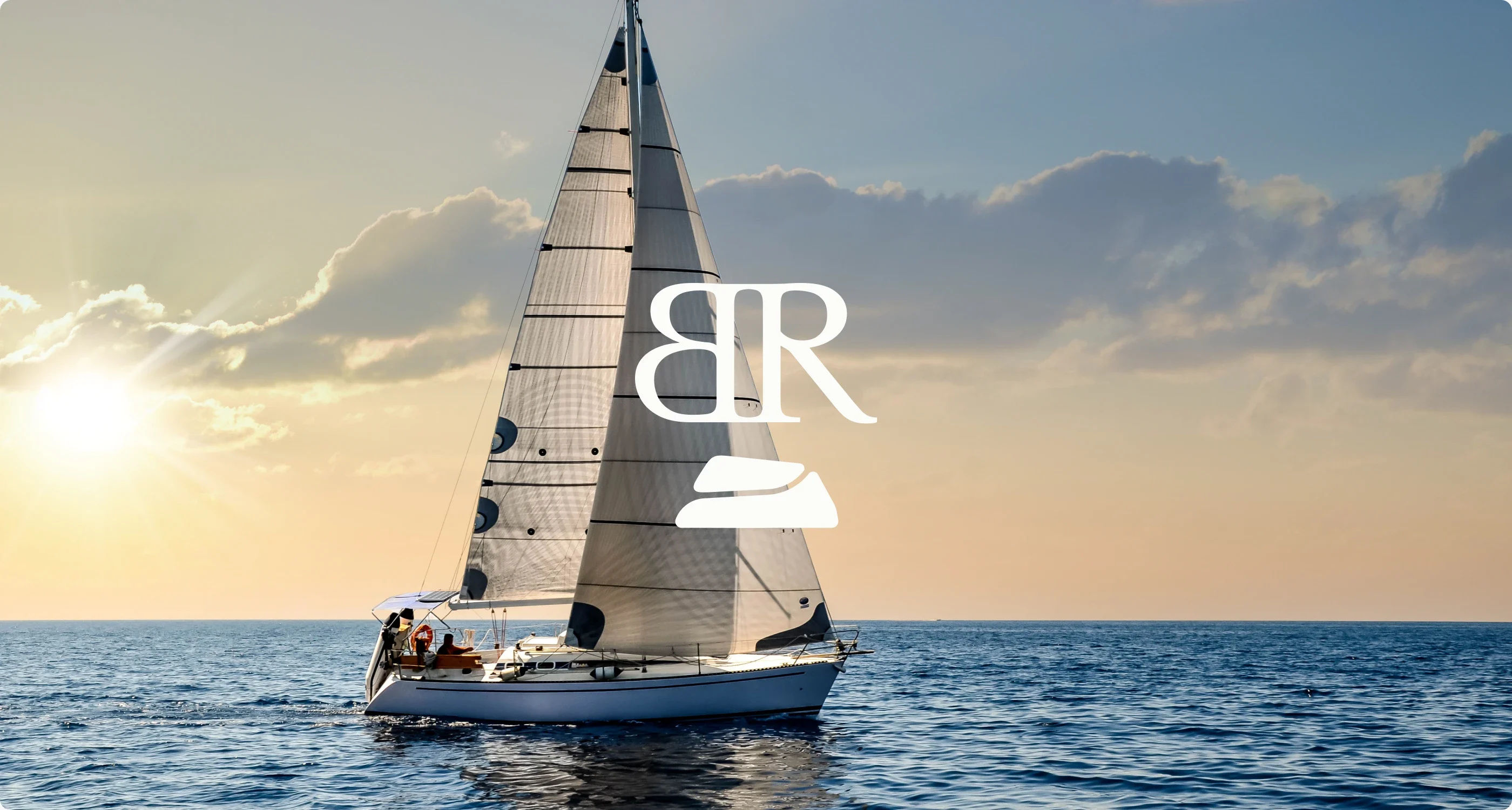 A sailing boat at sunset with the Bedrock monogram