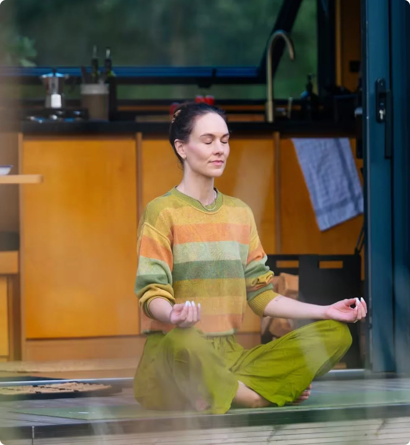 A woman meditating cross-legged inside a cabin
