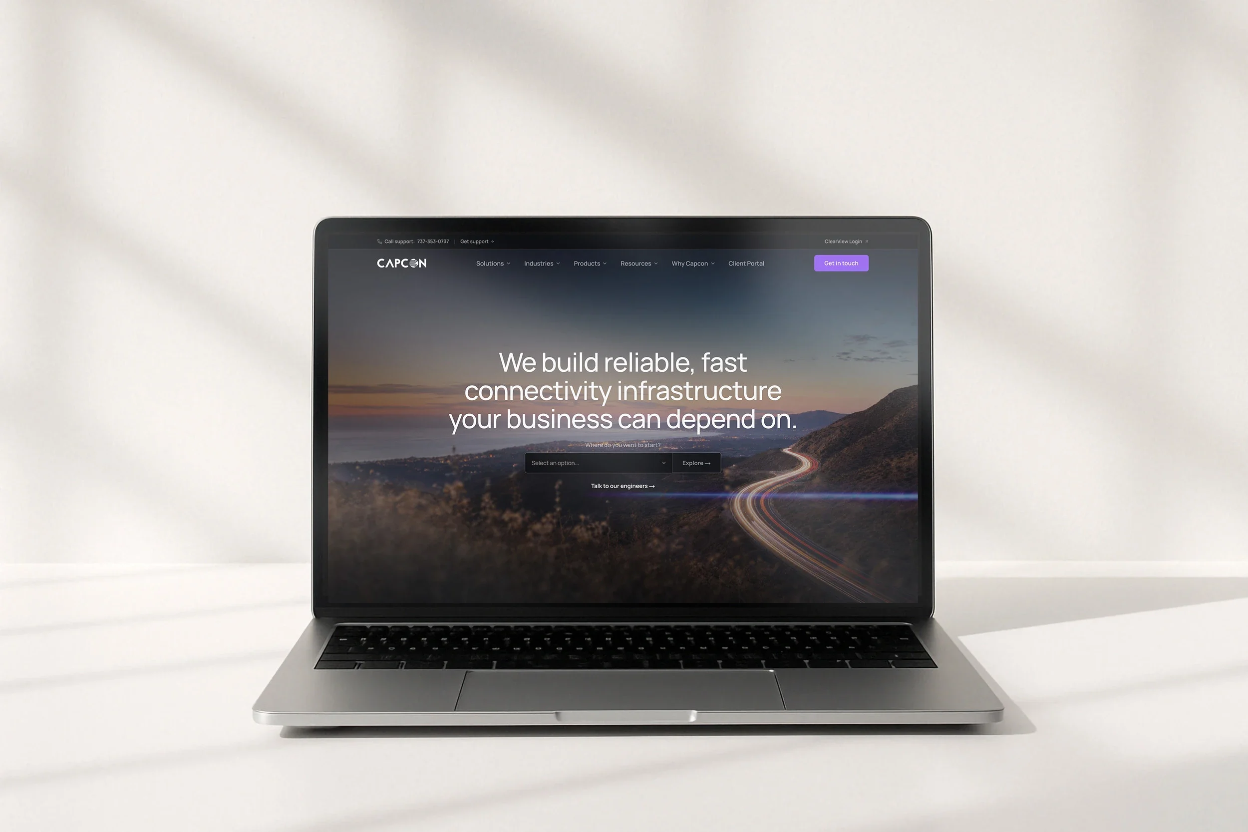 The Capcon home page, 'We build reliable, fast connectivity infrastructure your business can depend on', on a laptop on a white desk