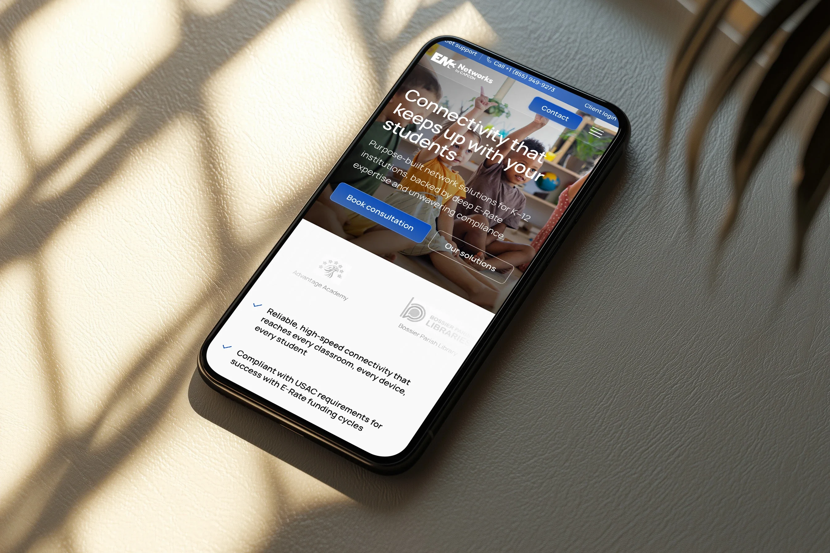 The K-12 page on a phone lying in sunlight: 'Connectivity that keeps up with your students'