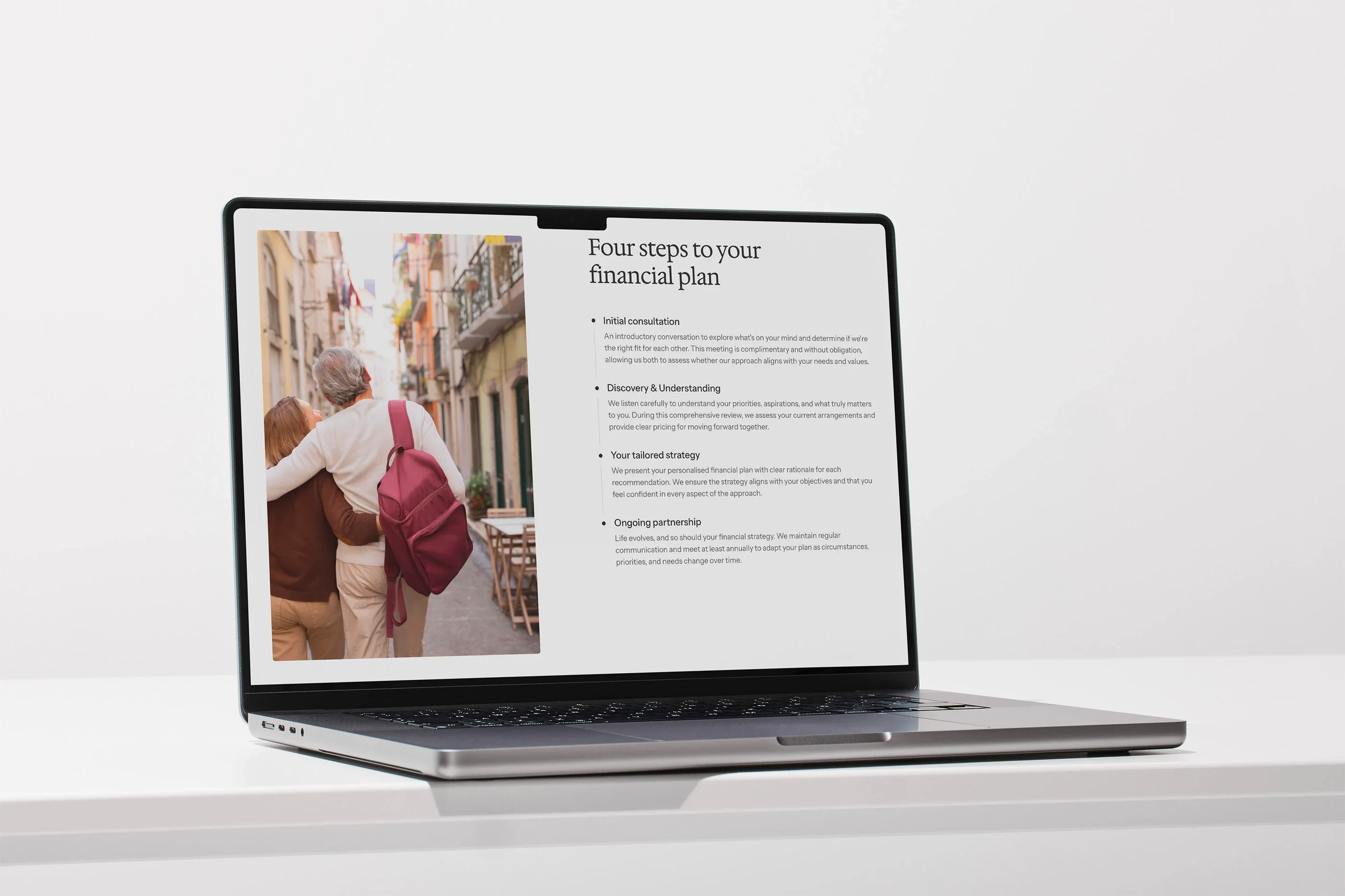 The home page's 'Four steps to your financial plan' on a laptop on a white desk, beside a photo of a couple walking down an old-town street
